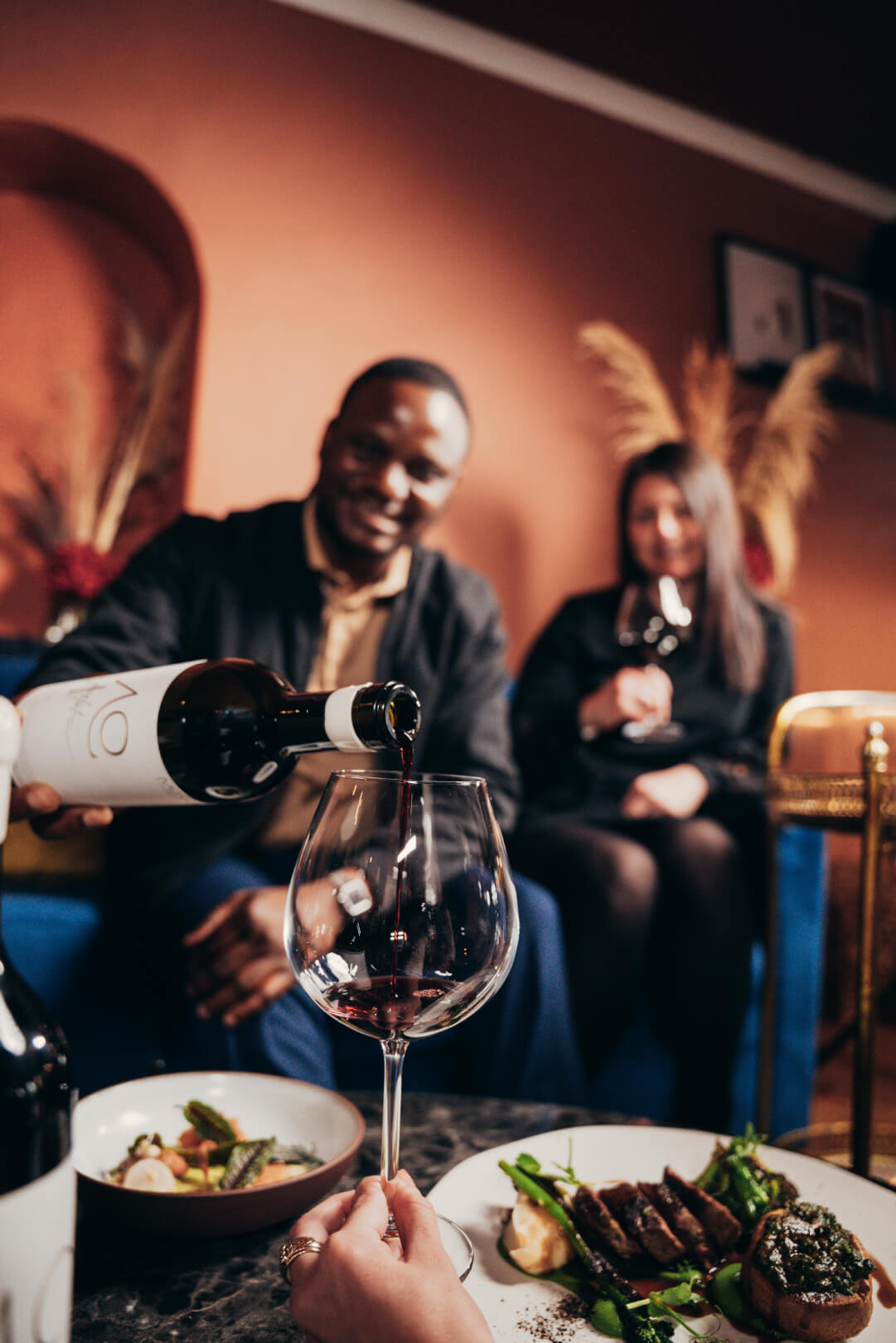 Tongai Joseph Dhafana pouring Mosi x Harry Hartman Bordeaux styled blend into a wine glass