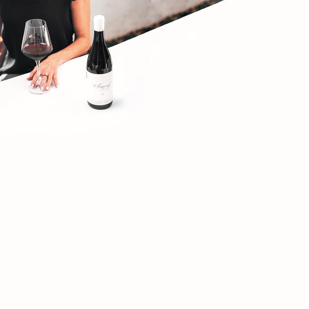 Harry Hartman Somesay, red wine, on a table and hands holding a red wine glass